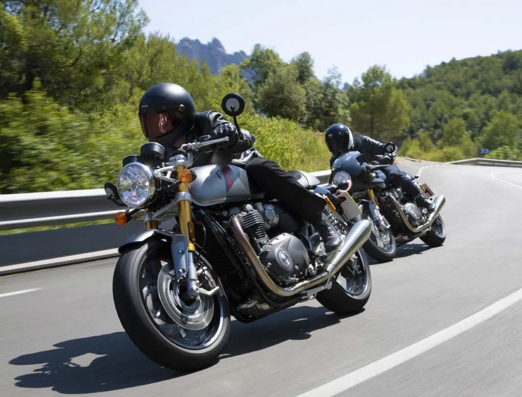 Triumph Thruxton RS motorcycle riders cornering together on their mountainous road adventure